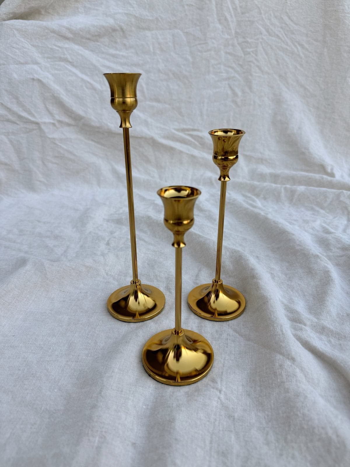 Brass taper candle holders grouped on a linen surface