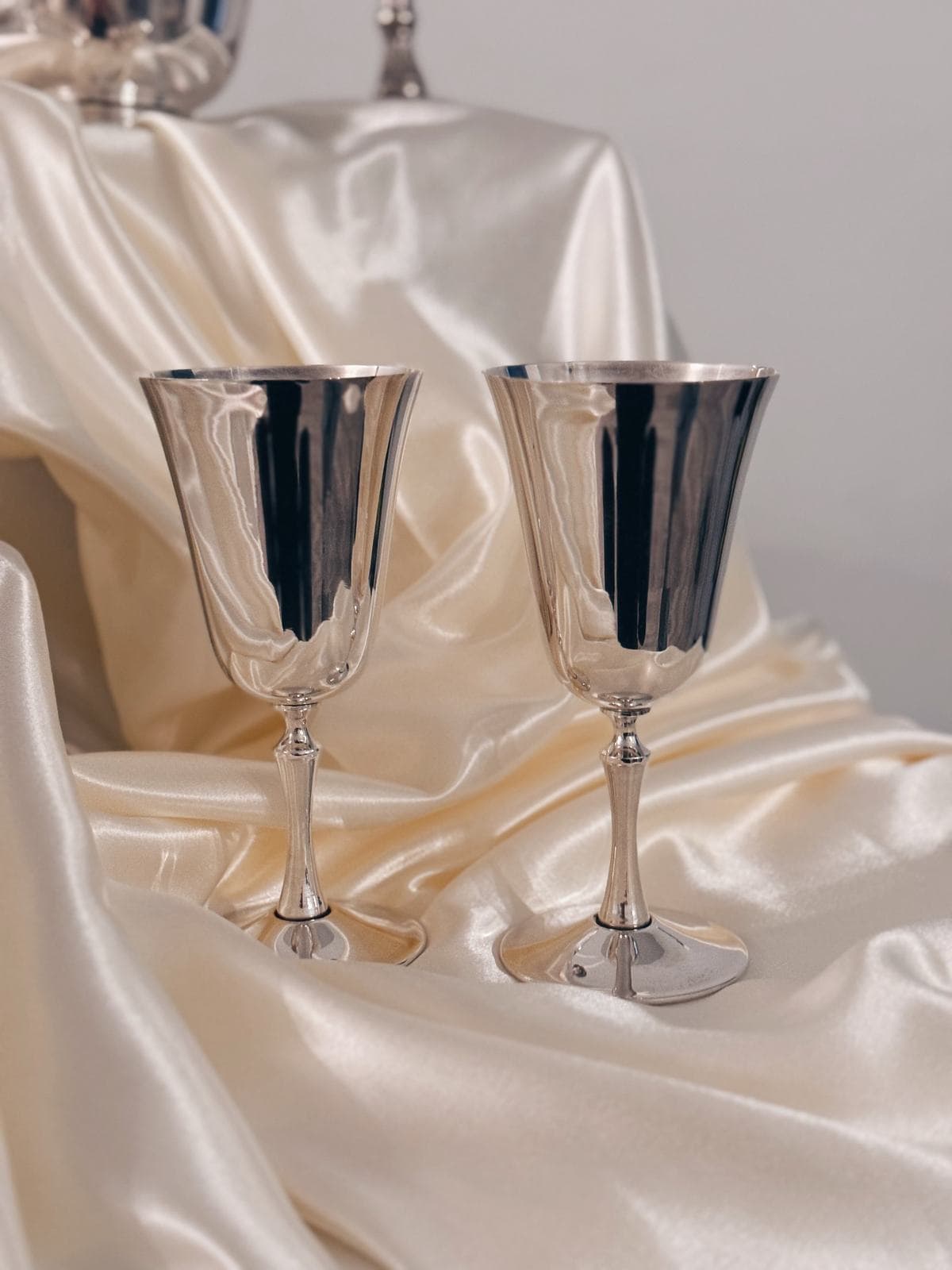A pair of silver goblets resting on cream satin