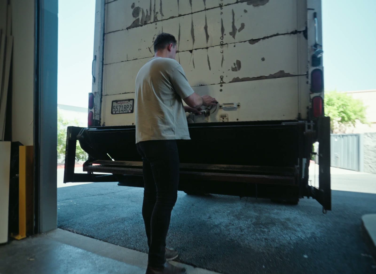 A crew member closing the roll-up door of the delivery truck at the warehouse