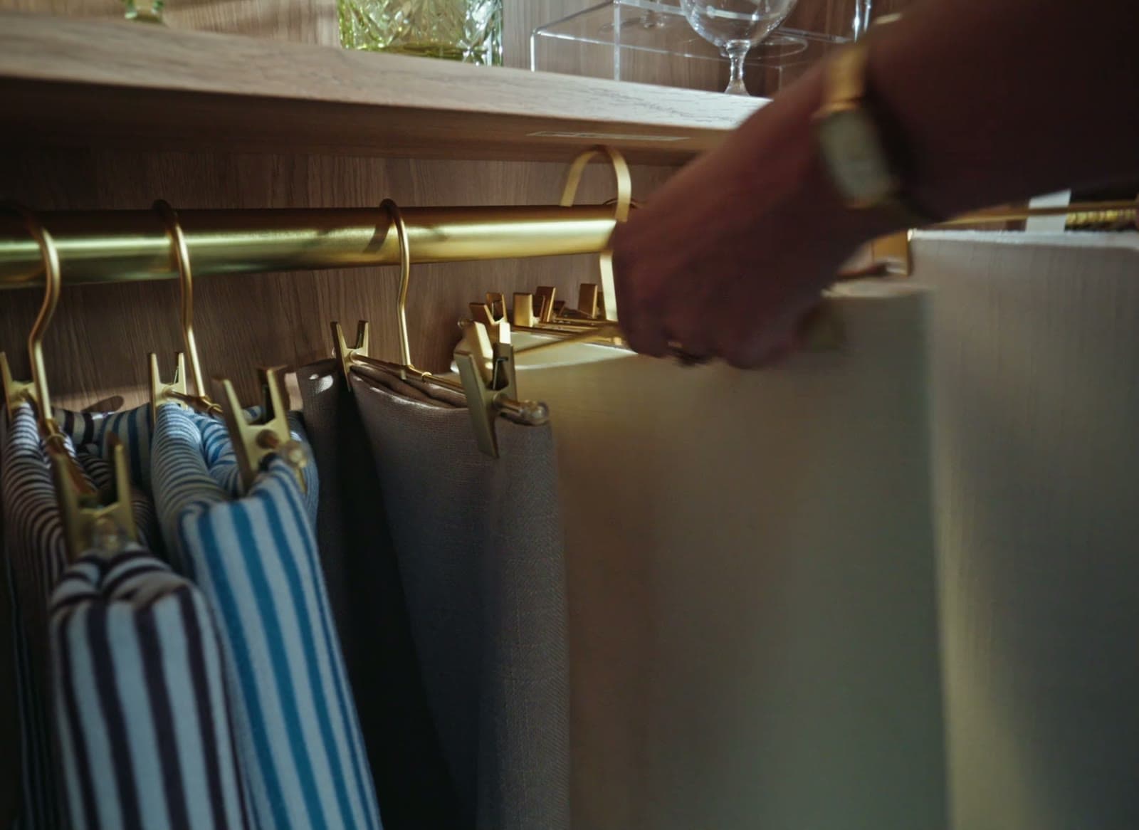 A hand drawing linen samples along a brass rail in the showroom