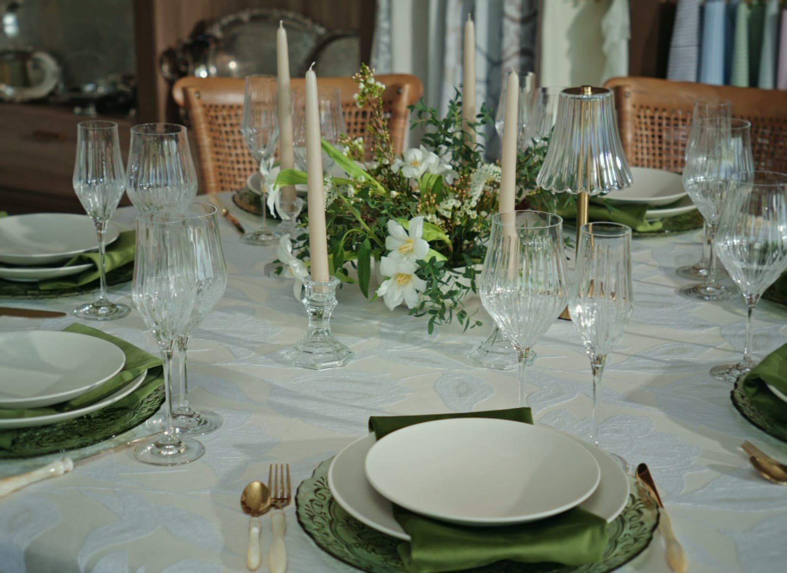 A table set in the showroom with green chargers, candles and crystal