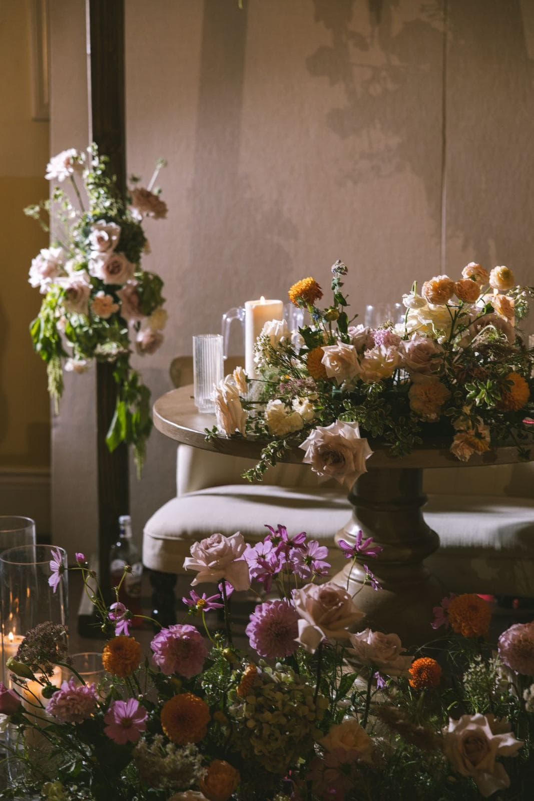 A sweetheart table surrounded by garden flowers and candlelight at dusk